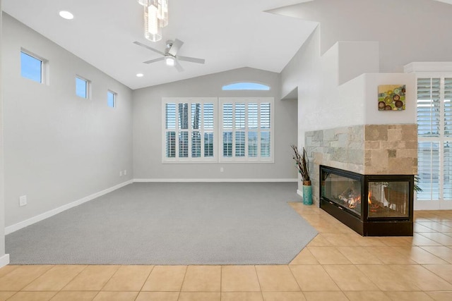 unfurnished living room with a multi sided fireplace, ceiling fan, light tile patterned floors, and lofted ceiling