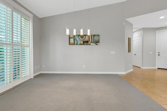 spare room featuring light carpet and lofted ceiling