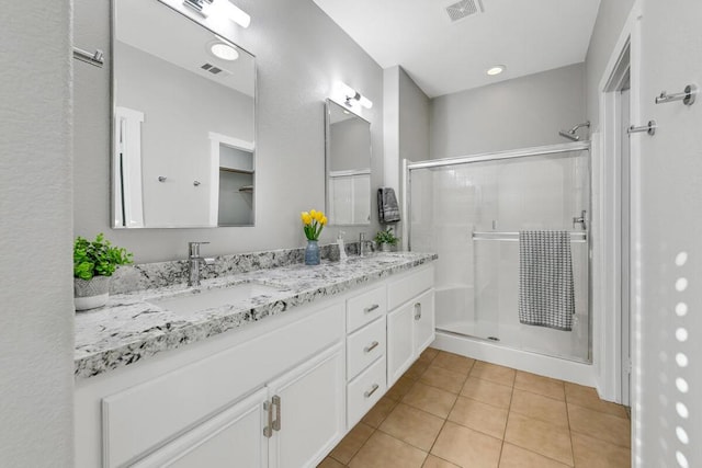 bathroom with tile patterned floors, a shower with door, and vanity