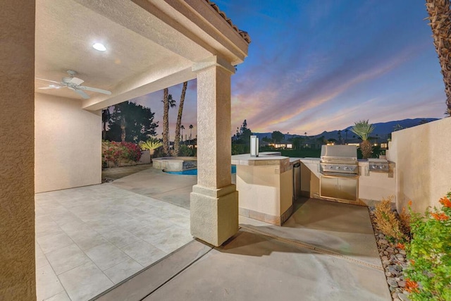 patio terrace at dusk featuring area for grilling and ceiling fan