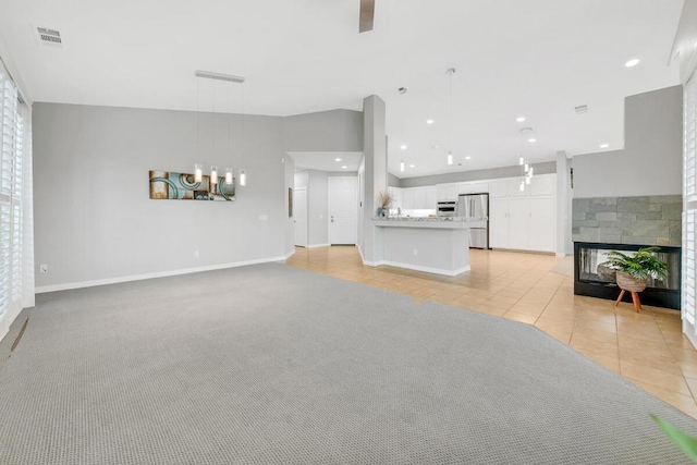 unfurnished living room featuring light carpet and a tiled fireplace