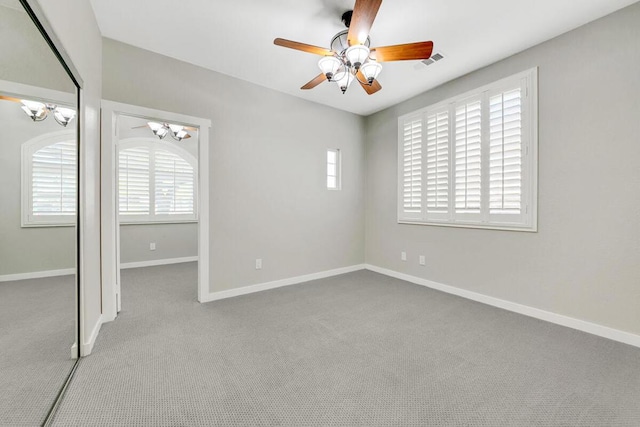 unfurnished room with ceiling fan with notable chandelier and light colored carpet