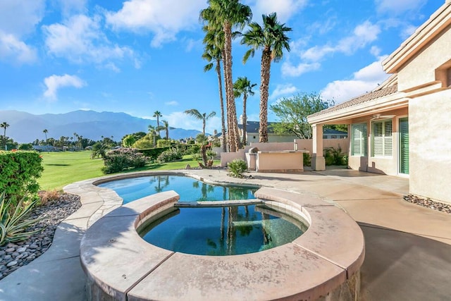 view of pool with an in ground hot tub, a mountain view, and a patio