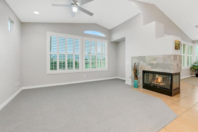 living room featuring a multi sided fireplace, light colored carpet, ceiling fan, and a healthy amount of sunlight