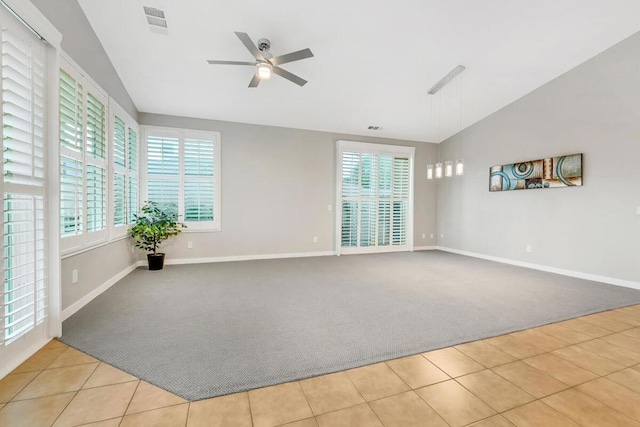 unfurnished room featuring a healthy amount of sunlight, ceiling fan, light colored carpet, and vaulted ceiling