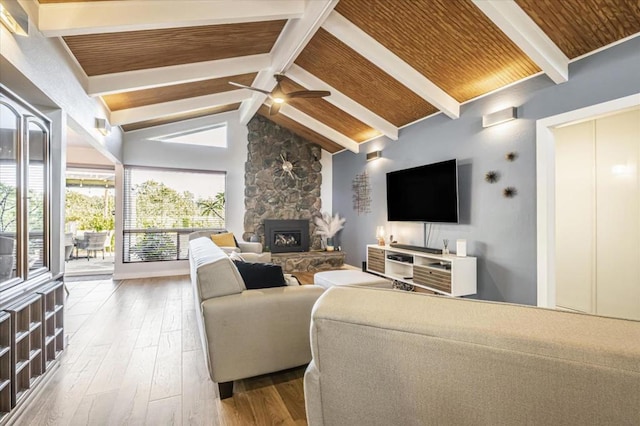 living room featuring ceiling fan, vaulted ceiling with beams, a fireplace, wood-type flooring, and wooden ceiling