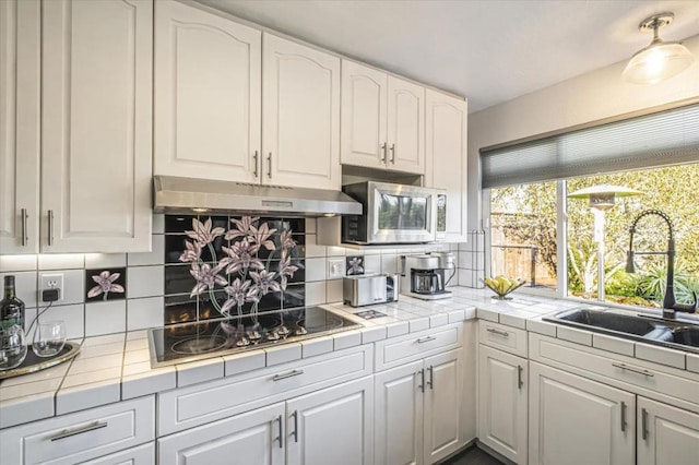 kitchen with black electric cooktop, sink, decorative backsplash, and white cabinets