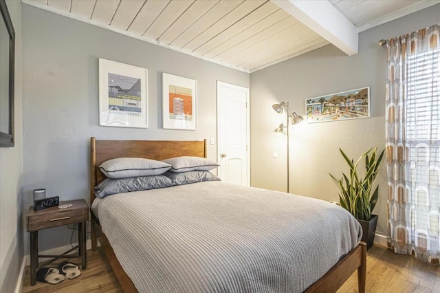 bedroom with beamed ceiling, hardwood / wood-style floors, and wood ceiling