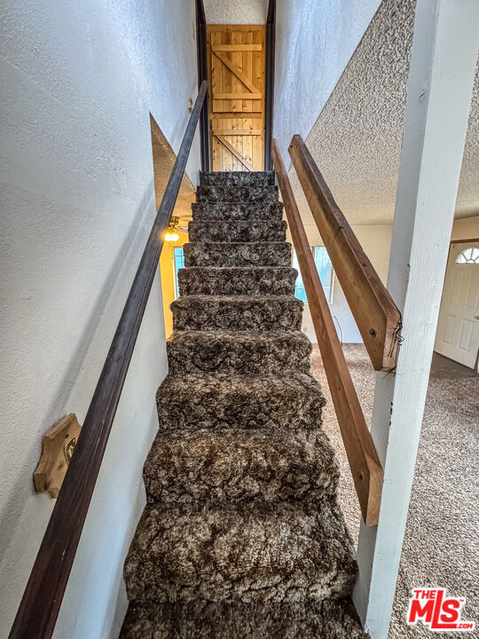 stairs featuring carpet flooring and a textured ceiling