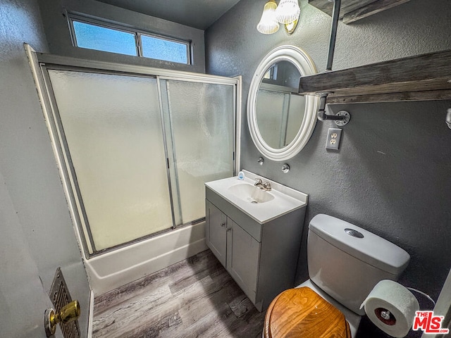 full bathroom with enclosed tub / shower combo, toilet, wood-type flooring, and vanity