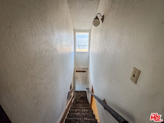 stairs featuring a textured ceiling