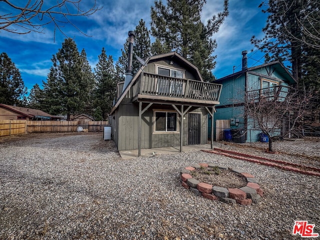 rear view of property featuring a wooden deck and a fire pit