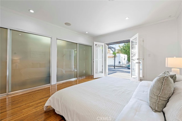 bedroom featuring wood-type flooring, crown molding, access to outside, and two closets