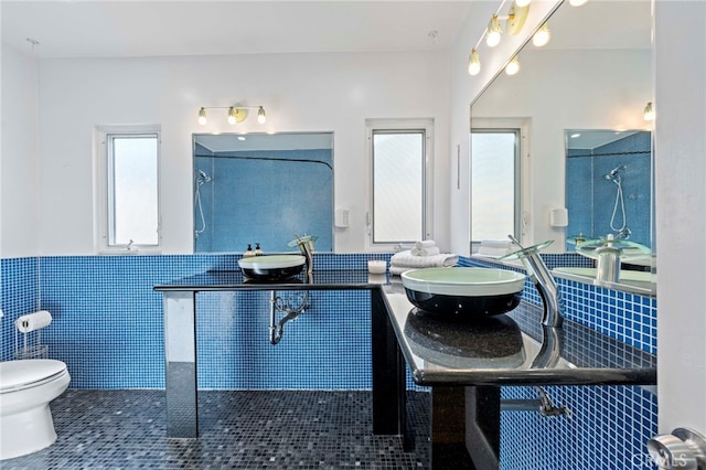 bathroom with tile patterned flooring, toilet, tile walls, and sink