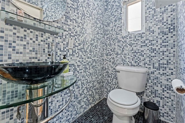 bathroom featuring sink, tile patterned flooring, toilet, and tile walls