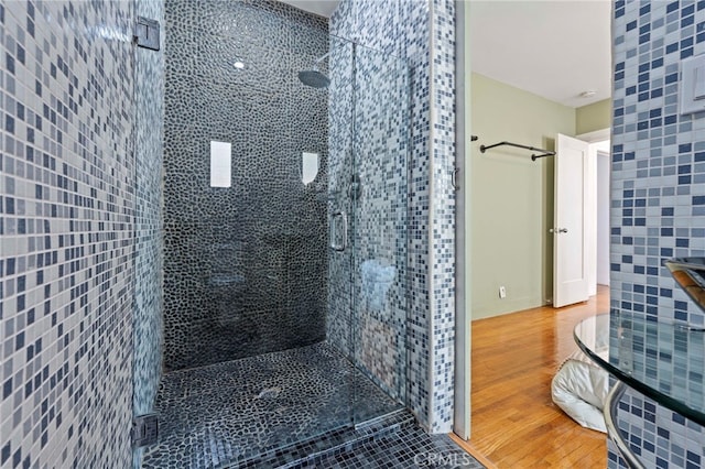 bathroom featuring a shower with shower door, tile walls, and hardwood / wood-style flooring