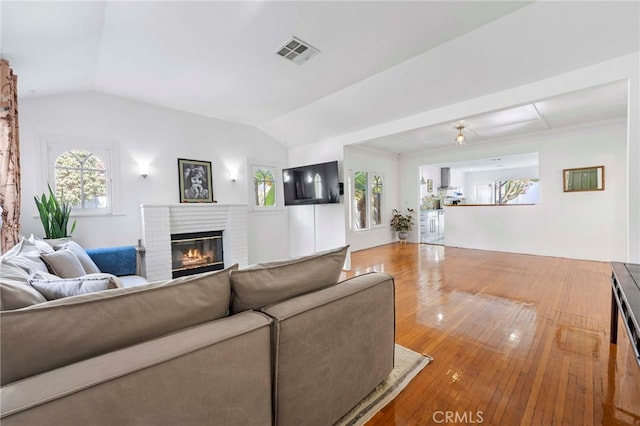 living room with a fireplace, hardwood / wood-style floors, and vaulted ceiling