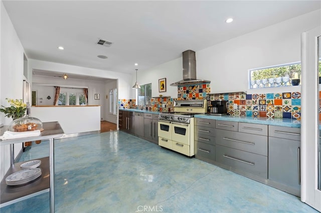 kitchen featuring gray cabinetry, sink, wall chimney exhaust hood, tasteful backsplash, and range with two ovens