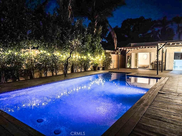 pool at night with a hot tub