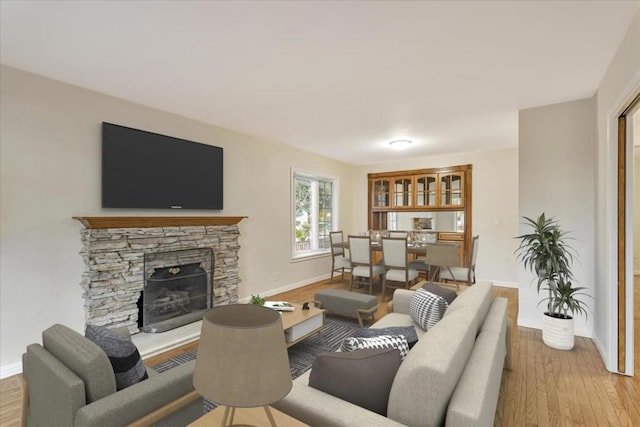 living room featuring a stone fireplace and light hardwood / wood-style flooring