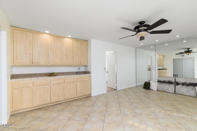 kitchen featuring light tile patterned flooring, light brown cabinetry, tile countertops, and sink