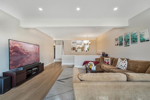 living room with a notable chandelier, light hardwood / wood-style floors, and beamed ceiling