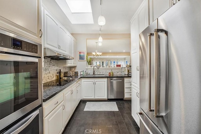 kitchen featuring a skylight, stainless steel appliances, tasteful backsplash, hanging light fixtures, and white cabinets