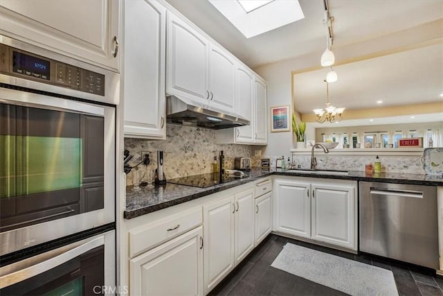 kitchen with pendant lighting, white cabinets, appliances with stainless steel finishes, a skylight, and sink