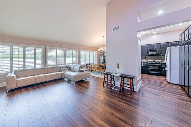 living room featuring dark hardwood / wood-style flooring, high vaulted ceiling, and a notable chandelier