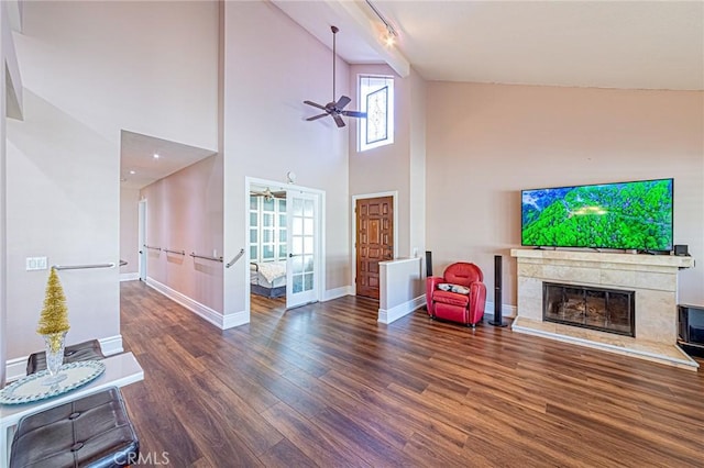 living room featuring a high end fireplace, track lighting, ceiling fan, high vaulted ceiling, and dark hardwood / wood-style floors