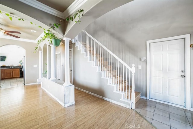 foyer entrance featuring ornate columns, ceiling fan, sink, crown molding, and light hardwood / wood-style floors