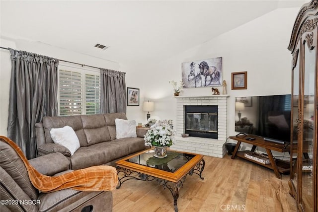 living room with lofted ceiling, a fireplace, and light hardwood / wood-style flooring