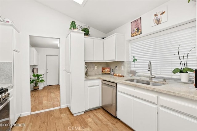 kitchen featuring lofted ceiling, sink, light hardwood / wood-style flooring, white cabinetry, and stainless steel appliances