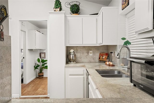 kitchen featuring white cabinets, light wood-type flooring, and sink