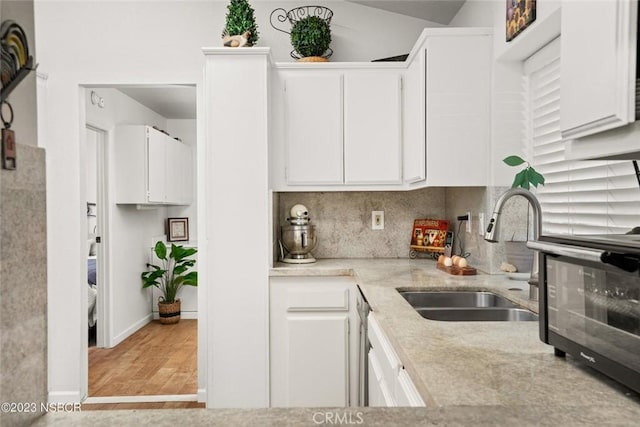 710 Crystal Way, Nipomo, CA 93444 - kitchen with white cabinets, light wood finished floors, backsplash, and light stone countertops