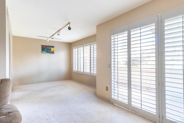 spare room featuring light colored carpet and rail lighting