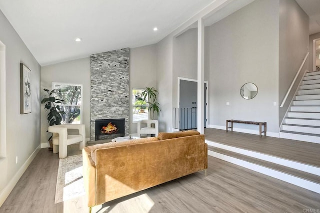 living room featuring high vaulted ceiling, light hardwood / wood-style flooring, and a fireplace