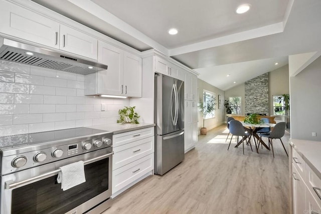 kitchen with vaulted ceiling, appliances with stainless steel finishes, white cabinets, and tasteful backsplash