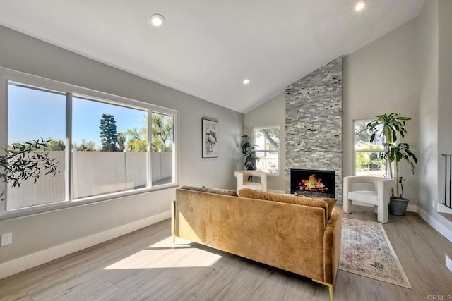 living room with light wood-type flooring, a fireplace, and high vaulted ceiling