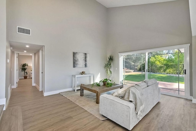 living room featuring a towering ceiling and light hardwood / wood-style flooring