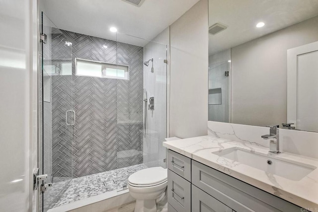 bathroom featuring toilet, vanity, and a shower with shower door