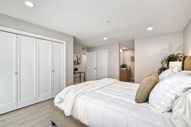 bedroom featuring connected bathroom, multiple closets, and light wood-type flooring