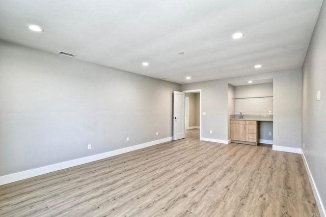 unfurnished living room featuring light wood-type flooring and built in desk