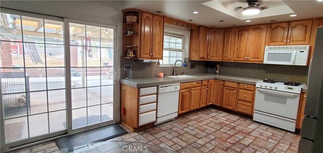 kitchen with backsplash, ceiling fan, sink, and white appliances