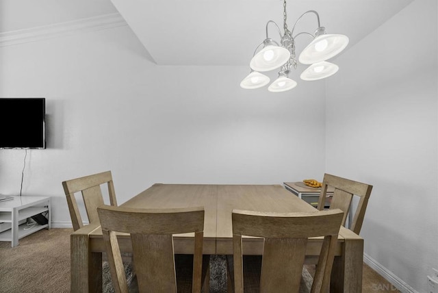 dining space with ornamental molding, dark carpet, and an inviting chandelier