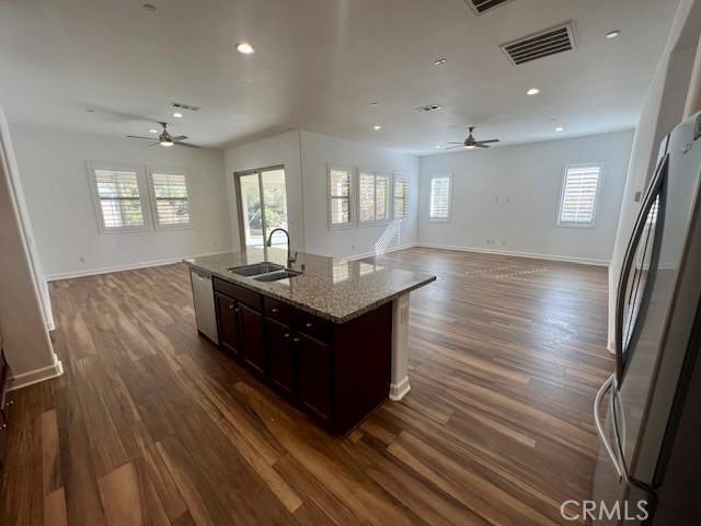 kitchen featuring dark wood-type flooring, sink, dark brown cabinetry, and a kitchen island with sink