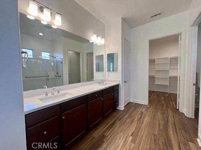 bathroom with walk in shower, vanity, and wood-type flooring