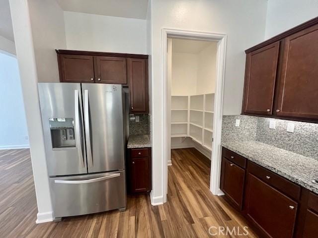 kitchen featuring hardwood / wood-style flooring, stainless steel refrigerator with ice dispenser, backsplash, light stone counters, and dark brown cabinetry