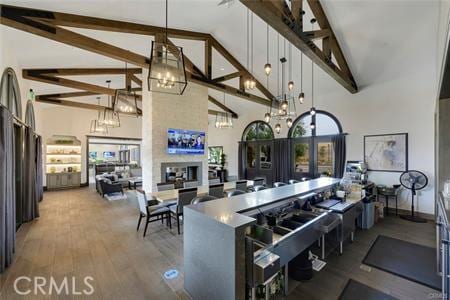 kitchen with high vaulted ceiling, decorative light fixtures, a fireplace, and hardwood / wood-style floors