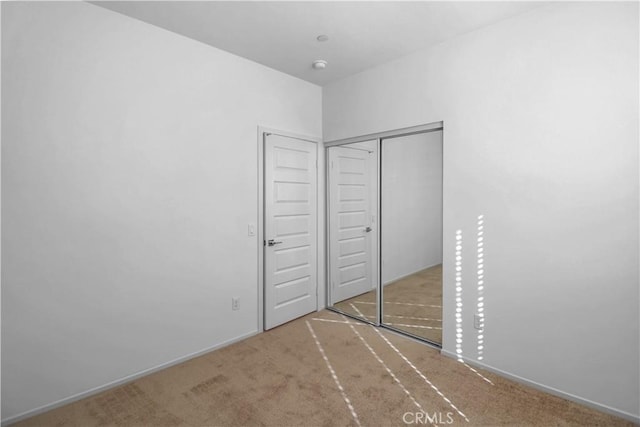 unfurnished bedroom with a closet and light carpet